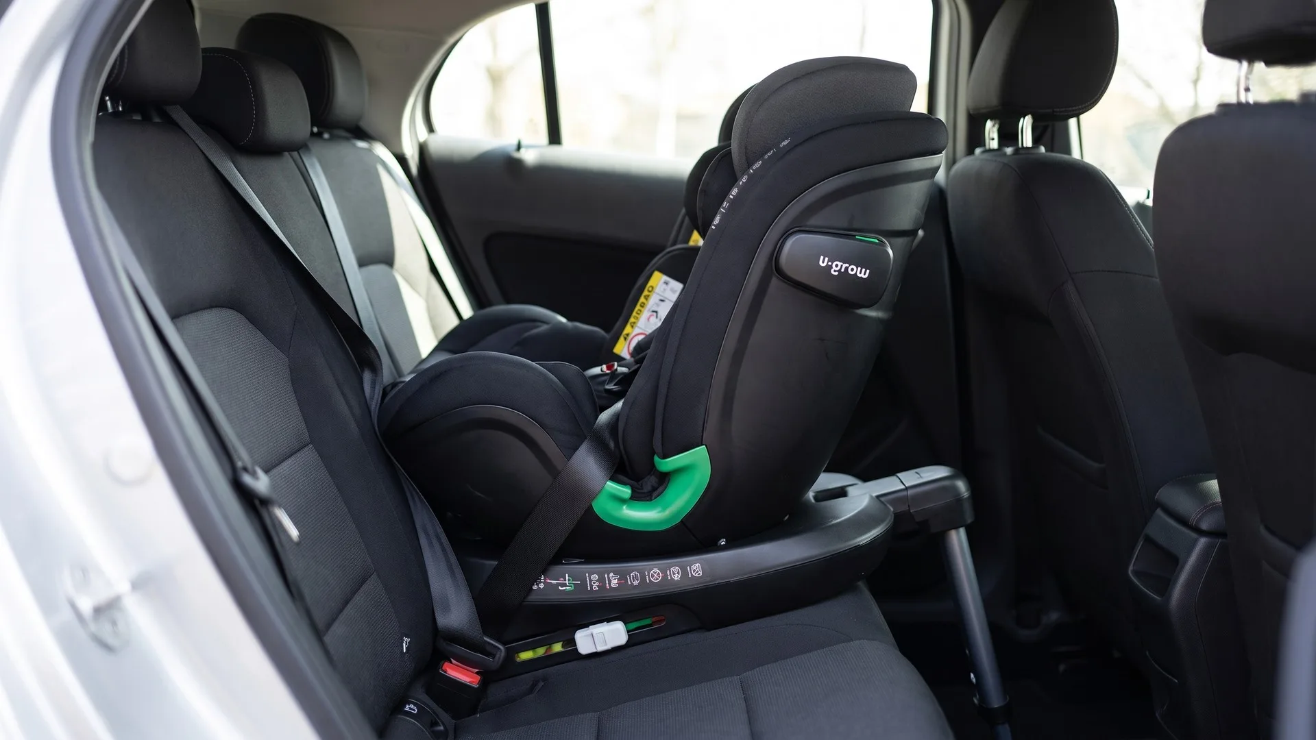 Scaun auto pentru copii prins pe Isofix pe bancheta din spate, cu piciorul de sprijin coborât pe podeaua mașinii