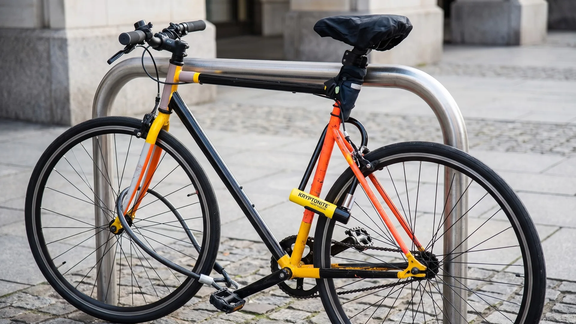 U-lock din oțel călit petrecut prin cadrul și roata din spate ale unei biciclete legate de un rastel stradal