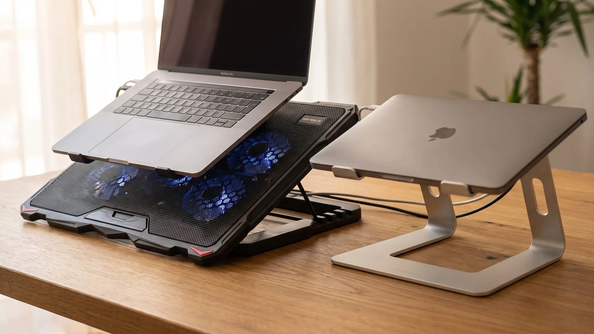 Laptop ridicat pe un stand pasiv, alături de un cooler cu ventilatoare, pe un birou