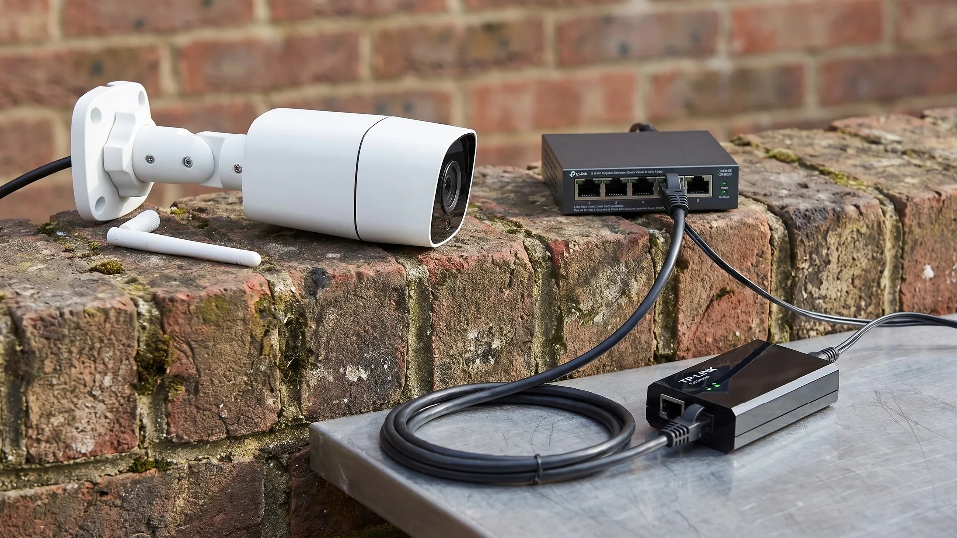 Cameră Wi-Fi de exterior afișată offline în aplicație, lângă un switch PoE și un cablu de rețea