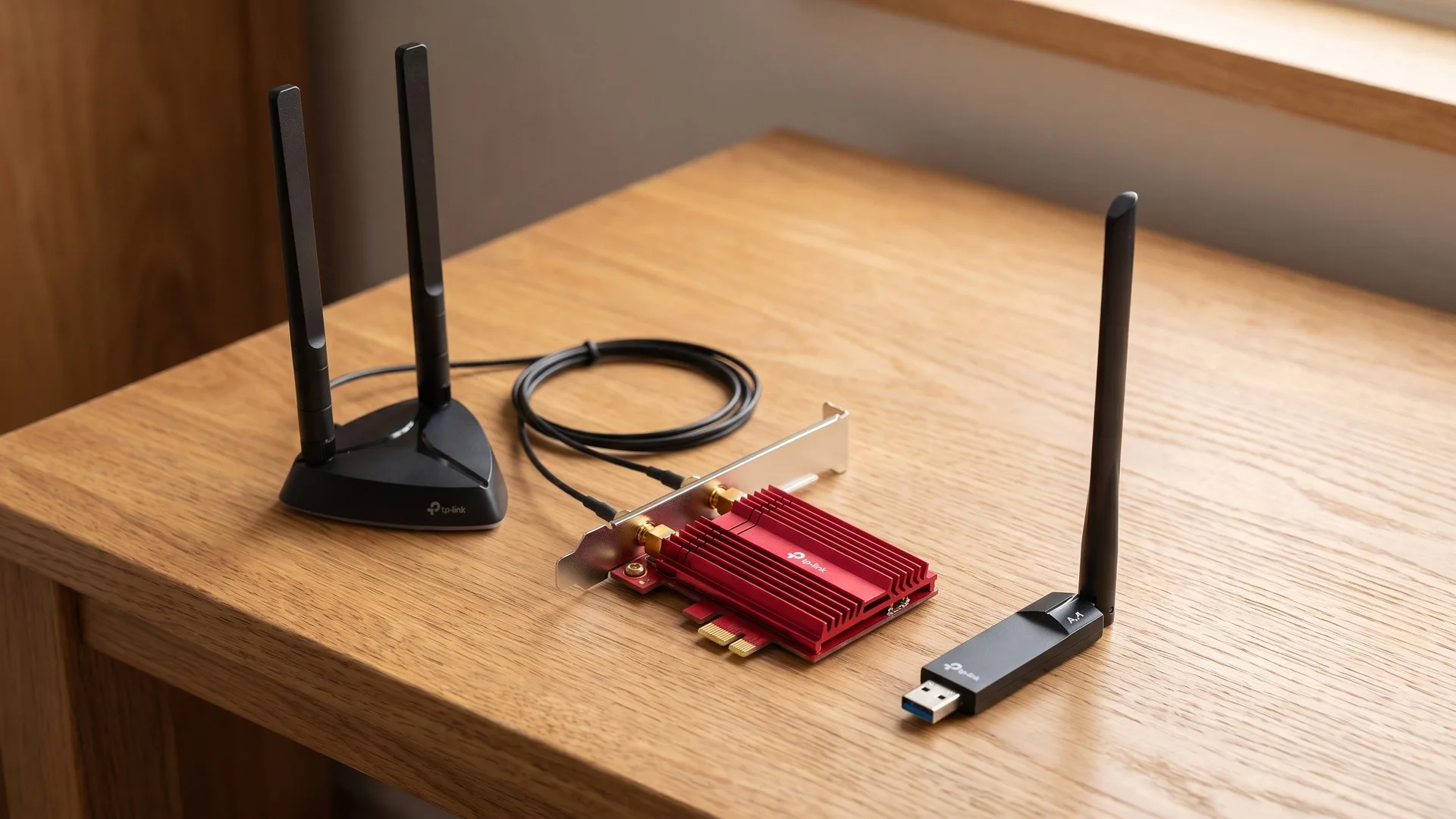 Placă de rețea Wi-Fi PCIe cu antene externe pe bază magnetică, lângă un adaptor USB compact